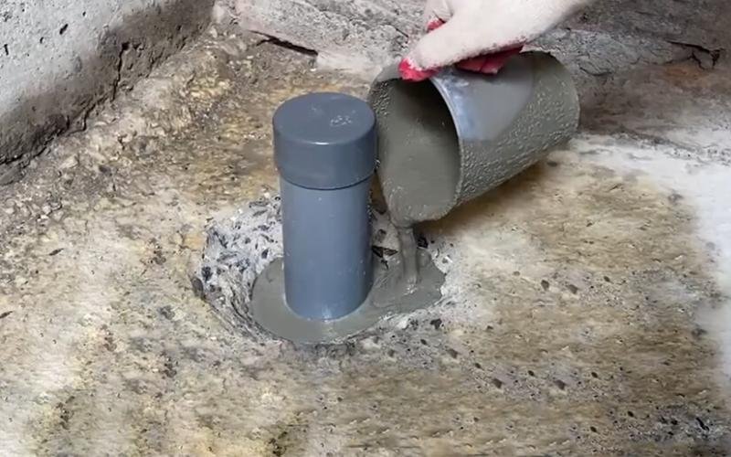 Technician sealing gaps around drain pipes to stop sewer odors entering the property.