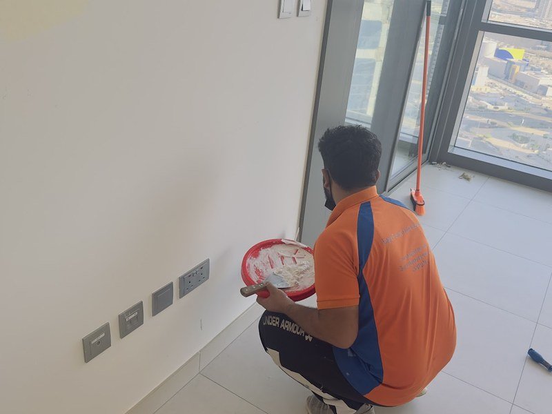 Eagle Trends painter preparing a wall for interior painting in Abu Dhabi